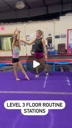 two girls are standing on a trampoline in the gym and one girl is holding her hand up