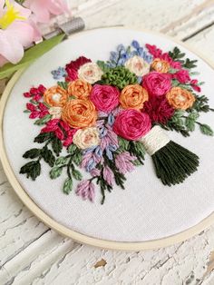 a bouquet of flowers on a white wooden table with pink and orange flowers in the background