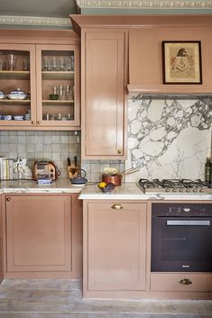 a kitchen with pink cabinets and marble counter tops