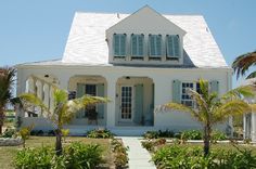 a white house with blue shutters and palm trees