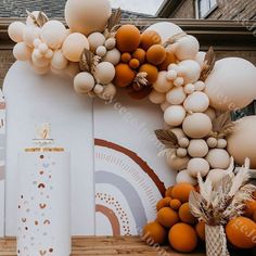 an arch made out of balloons and other decorations on a wooden floor next to a building