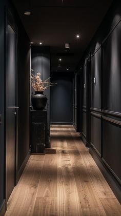 an empty hallway with dark walls and wooden floors is lit by recessed lights on the ceiling