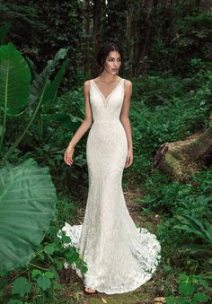 a woman standing in the woods wearing a wedding dress with an open v - neck