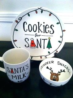 two mugs and a plate with cookies for santa written on the side, sitting on a table