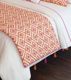 a bed with orange and pink pillows on top of it