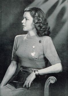 an old black and white photo of a woman sitting in a chair wearing a necklace