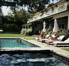 people are lounging in the sun by an outdoor swimming pool