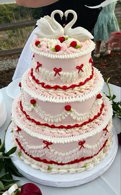 a three tiered wedding cake with swans on top