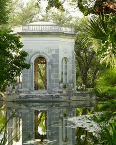 a gazebo in the middle of a pond surrounded by trees