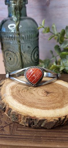 This gorgeous Split Shank Cuff Bracelet is made by Navajo Silversmith Artist Augustine Largo with Spiny Oyster.  The vibrant pinkish orange stone is set into a smooth vintage patina sterling silver bezel and surrounded by a beautiful twisted rope design and starburst on each side of the split shank cuff.   Spiny Oyster is often used in Native American Jewelry and is believed to bring good fortune and fertility making this the perfect gift for a friend or spouse for any special occasion! ★Specifics★ Metal: Sterling Stamped Size of Bracelet:  As the piece sets it will fit a 6 1/2" wrist and can be slightly adjusted up or down. Gap: 1 1/4" Width: 7/8" at most widest point, 1/4" at most narrow point Weight of Bracelet: 16g Hallmarked: AL (Augustine Largo) ★  Free shipping on all orders! We shi Southwestern Adjustable Cuff Bracelet With Natural Stones, Silver Southwestern Cuff Bracelet With Natural Stones, Southwestern Bangle Cuff Bracelet With Natural Stones, Southwestern Style Natural Stones Cuff Bangle, Southwestern Cuff Bracelet With Natural Stones As Gift, Southwestern Natural Stones Cuff Bracelet Gift, Western Style Cuff Bangle Bracelet Gift, Western Style Bangle Jewelry As Gift, Western Style Bangle Jewelry Gift