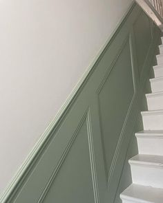 a cat sitting on top of a set of white stairs next to a green wall