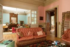 a living room with two couches and a rug on the floor in front of a mirror