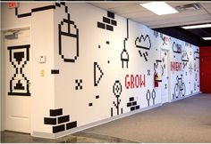 an office hallway decorated with black and white wallpaper, video game themed door covers and red doors