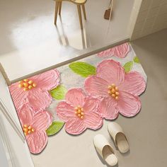 a pair of white shoes sitting on top of a floor next to a pink flower rug