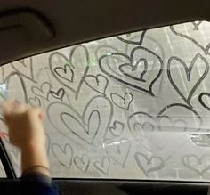 someone is drawing hearts on the windshield of a car