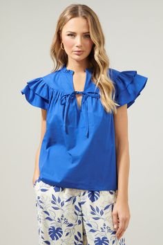 Spring classic. This solid, poplin top catches a breeze with ruffle layered cap sleeves that frame a split neckline. A tie sits along the lower part of the split , while the bodice maintains a relaxed fit. Wear it out on a warm day, tucked into your favorite high rise pants- Lightweight- Cap sleeves- Split neck- Relaxed fit- Comes in 3 colorsSize + Fit - Model is 5'11" and wearing size XS- Measurements taken from size S - Chest: 21"- Inseam: 24" Fabric Self: 100% Cotton Style Number STT16755A Elegant Poplin Tops With Spread Collar, Classic Poplin Tops With Spread Collar, Collared Poplin Top With Button Closure, Formal Button-up Poplin Tops, Luxury Poplin Button-up Tops, Tie Front Blouse, Casual Preppy Outfits, High Rise Pants