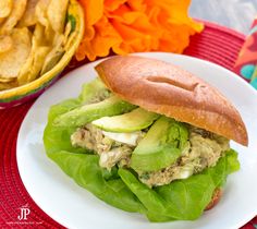 a chicken salad sandwich with lettuce and avocado on a white plate