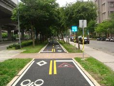 an empty bike lane on the side of a street with trees and buildings in the background