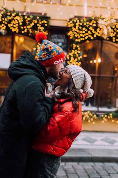 a man and woman kissing in front of christmas lights