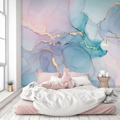 a bed with pink and blue pillows in front of a wall mural