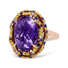 There are no words to truly describe this vividly colorful ring set in 18K Yellow and Rose Gold. The ring starts with a masterfully cut, checkboard purple amethyst set with 4 claw prongs. This magnificent purple stone measures 12mm x 11mm and gives off flashes of deep purple. The centerpiece is then finished with a yellow gold halo complete with a dazzling array of blue and yellow sapphires and white diamond accents. The entire piece sits on a rose gold band. You’ll never see another ring like t Luxury Multicolor Amethyst Ring With Gemstone Accents, Multicolor Oval Amethyst Ring, Purple Multi-stone Sapphire Ring, Multicolor Oval Amethyst Ring With Gemstone Accents, Elegant Multicolor Amethyst Gemstone Ring, Luxury Purple Sapphire Jewelry, Multicolor Luxury Amethyst Ring, Elegant Multicolor Amethyst Ring With Gemstone Accents, Elegant Multicolor Amethyst Ring With Accent Stones