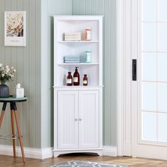 a white shelf with bottles and soaps on it next to a table in a room