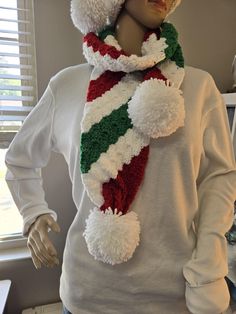 a mannequin wearing a hat and scarf with pom - poms on it