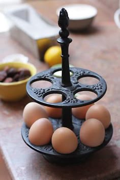 an egg holder with six eggs in it on a table next to bowls and plates