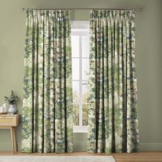 a living room with green curtains and a white rug in front of the window that has an image of flowers on it