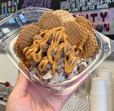 a person holding up a waffle sundae in a plastic container