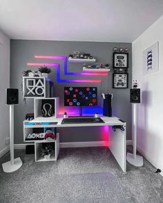 a desk with speakers and a computer on top of it in front of a wall