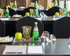 an empty restaurant table is set up with green and yellow bottles, silverware, and glasses