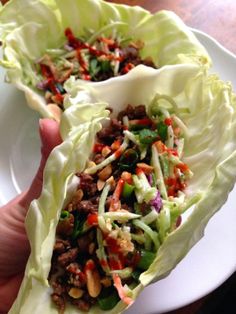 two lettuce wraps filled with meat and veggies on a white plate