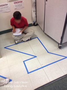 a man sitting on the floor in front of a refrigerator with blue tape taped to it