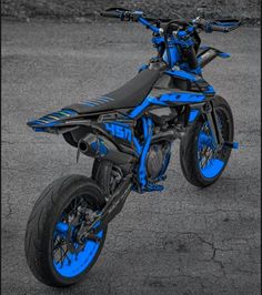 a blue dirt bike parked on top of a parking lot