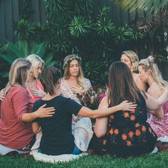 a group of women sitting on top of a lush green field next to each other