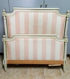 a pink and white striped bed frame on the floor next to a wall with a mirror above it