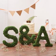 the letters are made out of moss and have pine cones on top of them for decoration