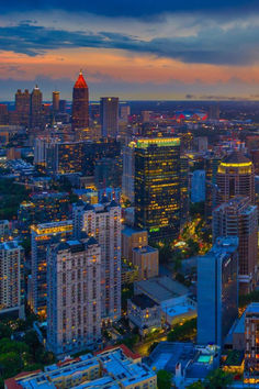 the city skyline is lit up at night, with tall buildings in the foreground