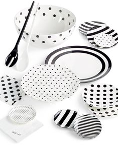 black and white polka dot plates, cups, spoons and utensils on a white surface