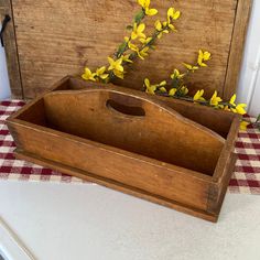 a wooden tray with yellow flowers in it on a checkered tableclothed table cloth