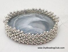 a silver beaded dish on a white surface