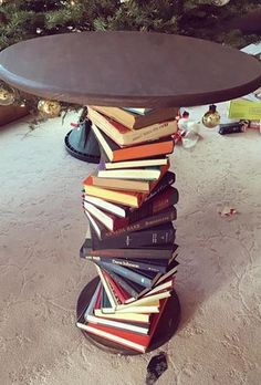 a stack of books sitting on top of a wooden table next to a christmas tree