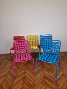 four colorful chairs sitting on top of a wooden floor