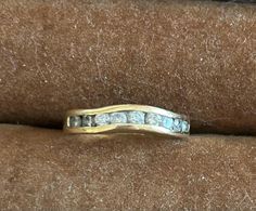 a gold ring with white diamonds on it sitting on top of a brown velvet surface