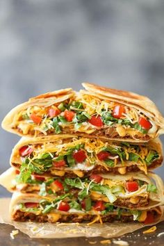 three quesadillas stacked on top of each other with cheese, lettuce and tomatoes