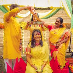 three women dressed in yellow and red posing for the camera with one woman holding a tray over her head