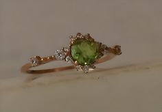 a ring with an oval cut green stone surrounded by small white and yellow diamonds on top