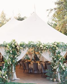 a white tent with tables and chairs covered in greenery