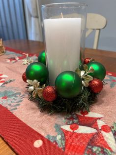 a candle sitting on top of a table next to christmas decorations and baubles